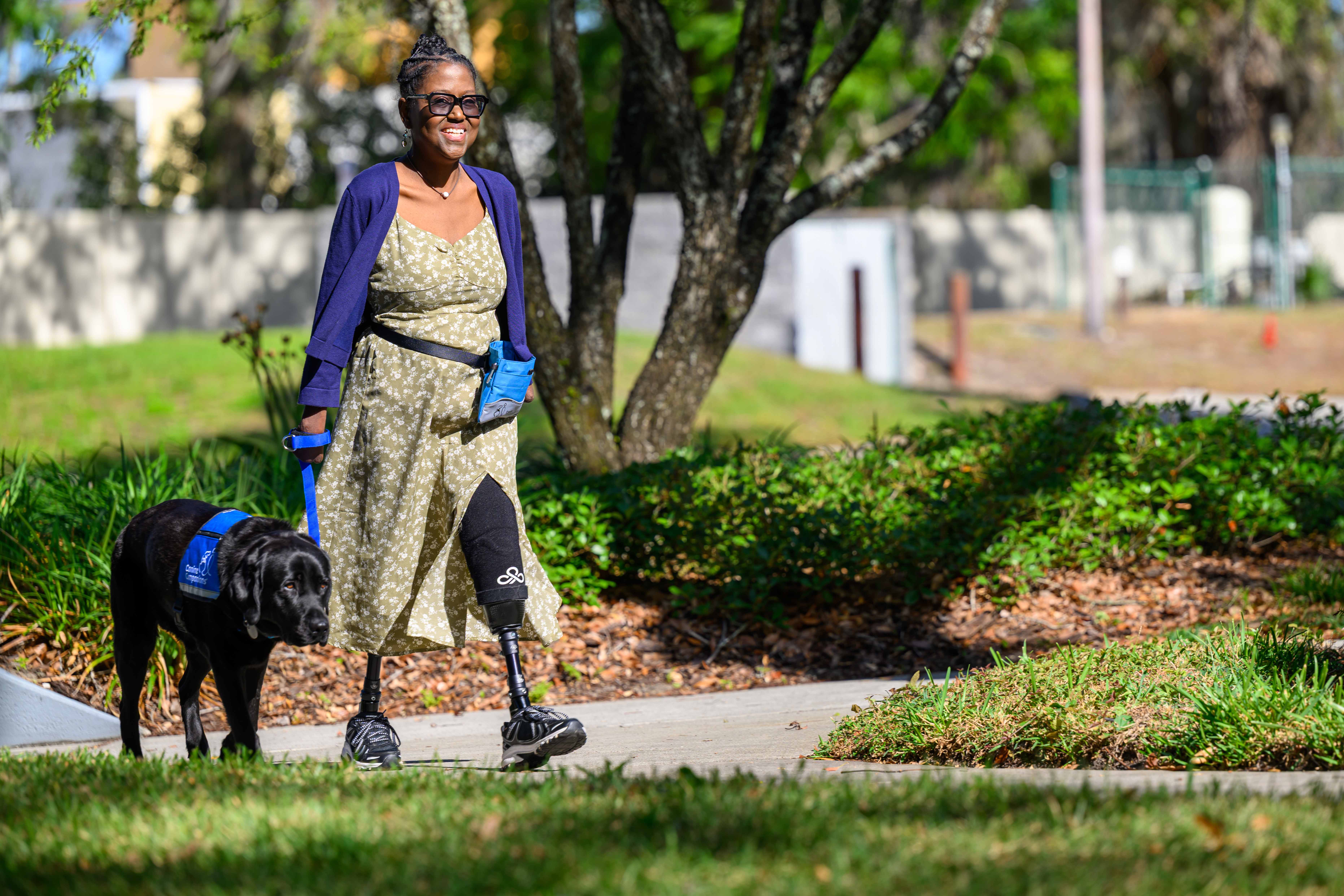 A woman with prosthetic legs walks with a service dog